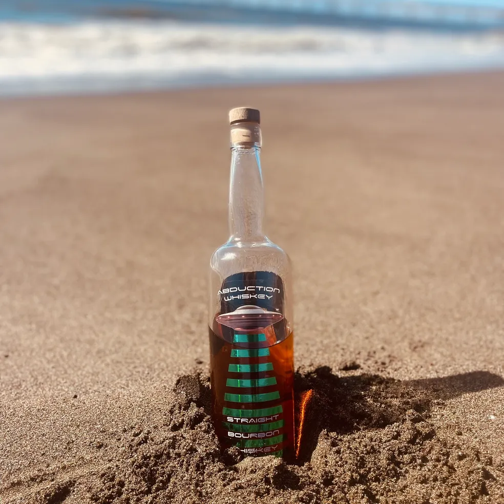 Abduction Whiskey bottle planted in the sand at the beach